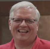 Photo of smiling Man with white hair, glasses, and red shirt