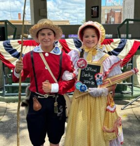Korbin Asbury as Tom Sawyer in a red patterned shirt and Ainsley Ahrens in a yellow and pink patterned dress.