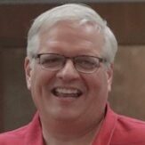 Photo of smiling Man with white hair, glasses, and red shirt